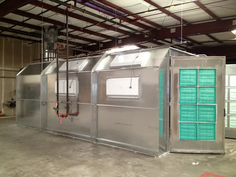Warehouse interior with a large metal-panel enclosure being installed