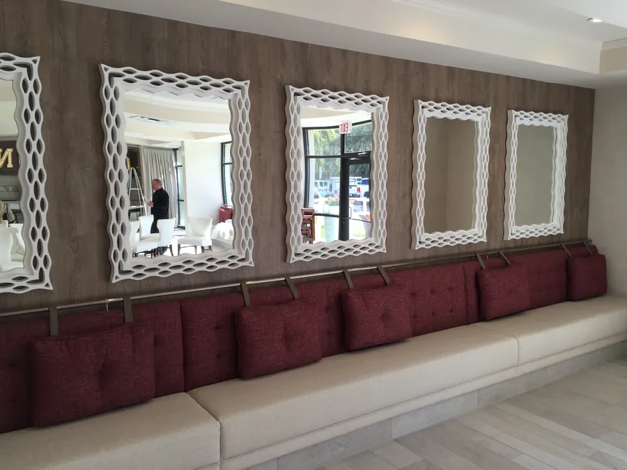 Finished interior with a long upholstered banquette under a row of white framed mirrors
