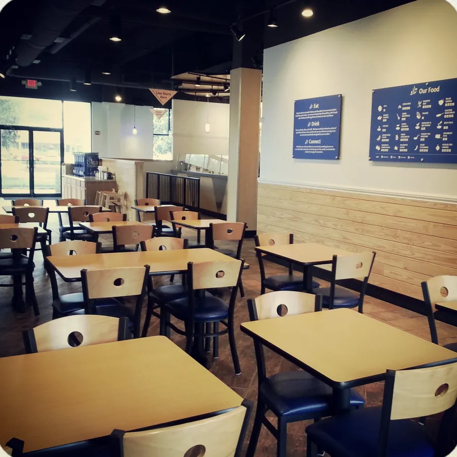 Fast-casual restaurant dining room with wood tables and menu boards