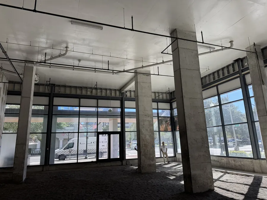 Empty commercial shell space with storefront glazing and an open ceiling